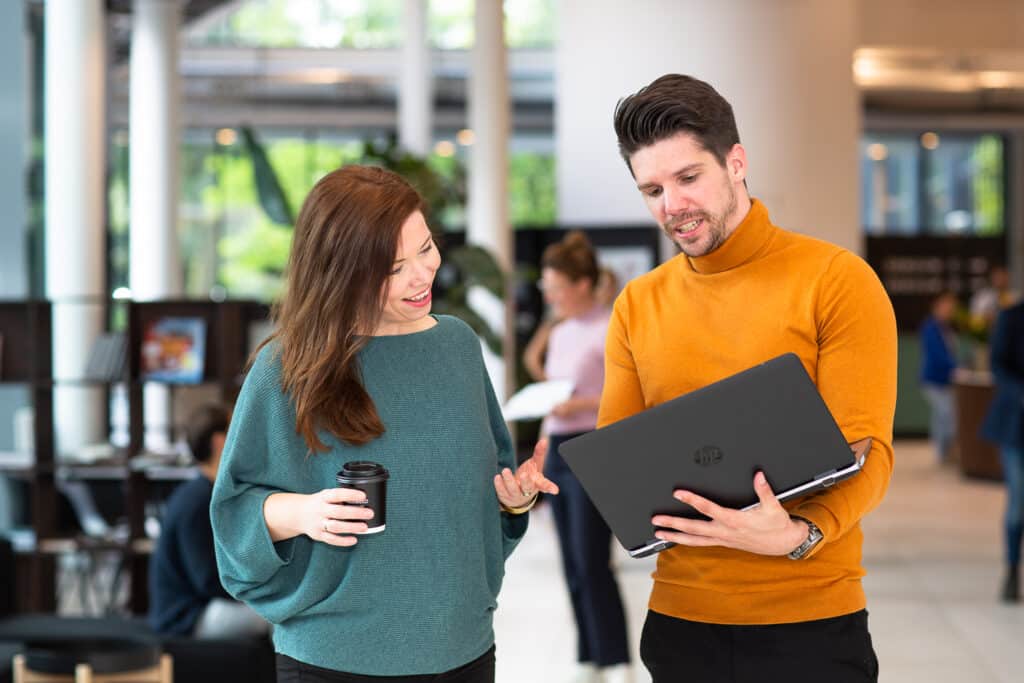 Man en vrouw overleggen staand op kantoor met laptop