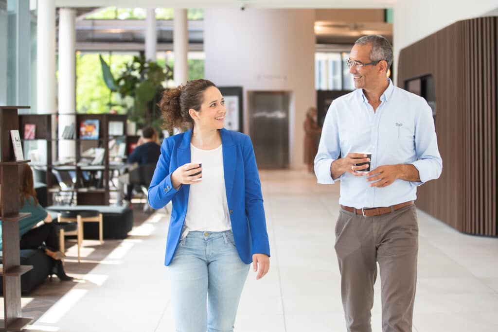 Man en vrouw lopen door kantoorgang met koffie
