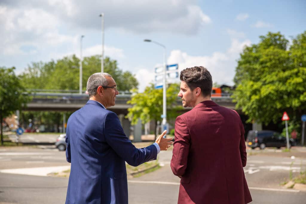 Twee mannen staan op straat te praten.