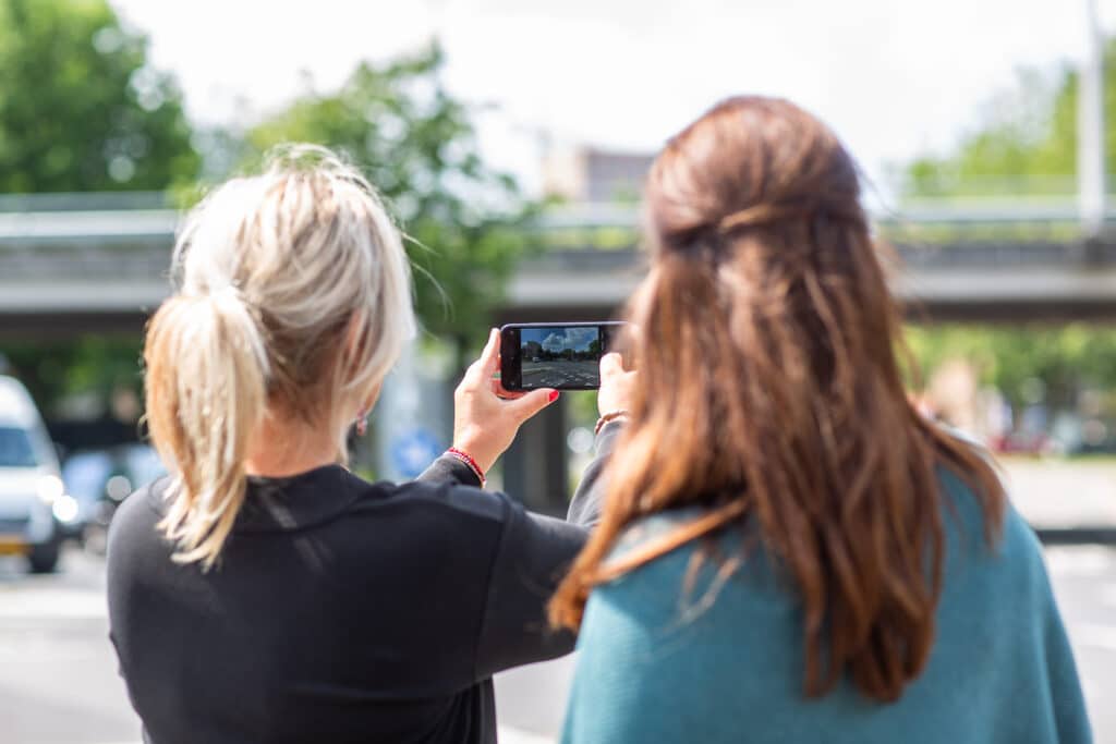 Twee vrouwen maken een foto van de weg met een smartphone.