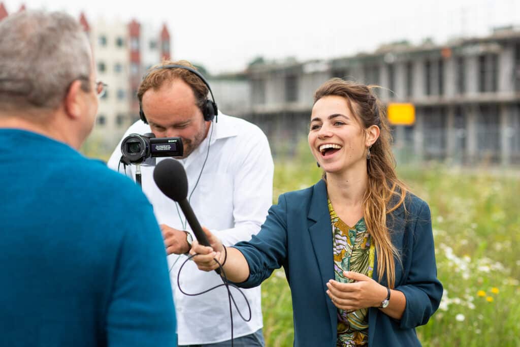 Man met camera en vrouw met microfoon interviewen andere man