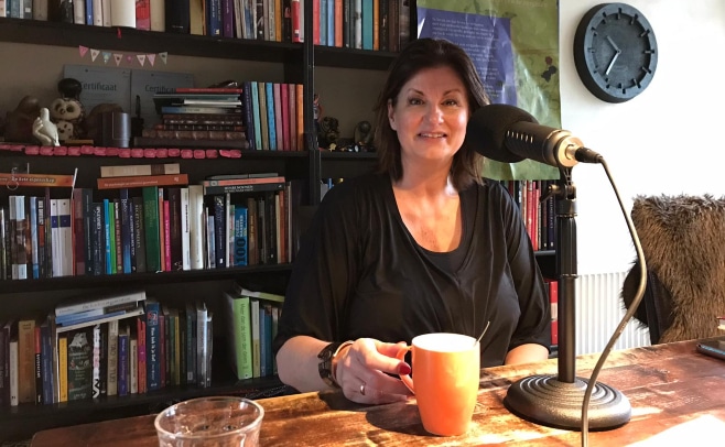 Vrouw neemt podcast op voor boekenkast