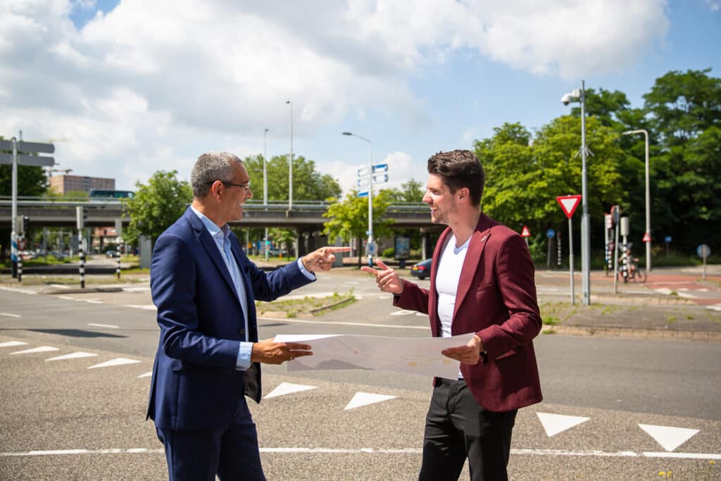 Twee mannen overleggen buiten met een grote plattegrond