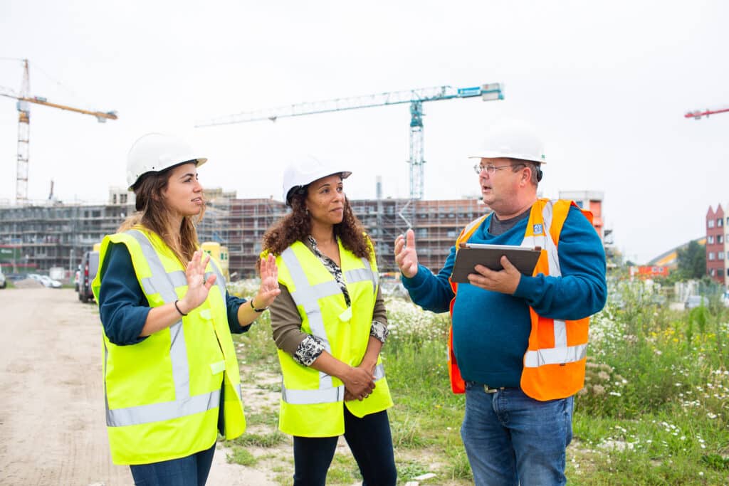 Drie personen overleggen op de bouwplaats