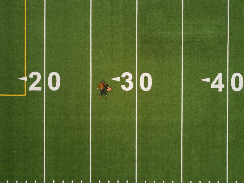 Een persoon ligt op een voetbalveld met daarop de nummers 20, 30 en 40