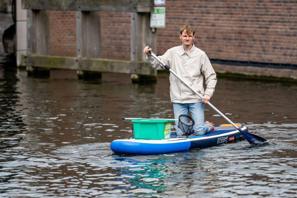 Sander Koster van Future Communication vist suppend zwerfafval uit het water in Den Haag