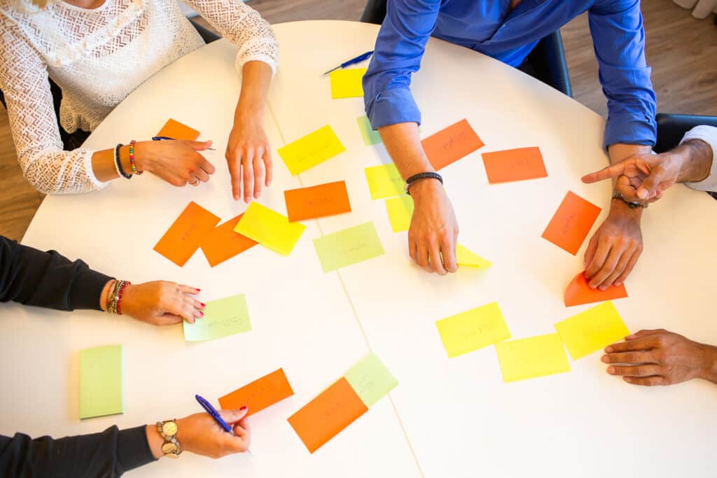 Drie personen leggen gekleurde post-its op tafel