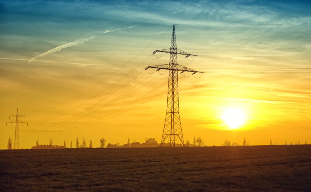 Elektriciteitsmast in een open veld met op de achtergrond de zonsopkomst